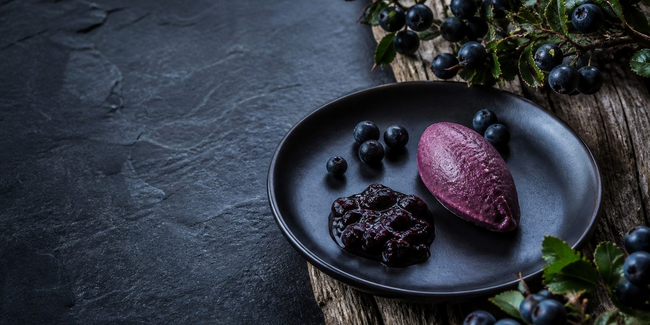 Calafate fruit and a violet calafate preparation on a dark plate